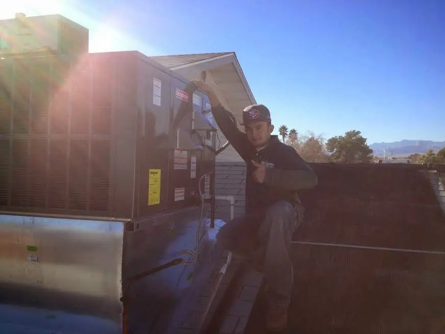 HVAC technician performing HVAC Inspection on a rooftop unit in Newton